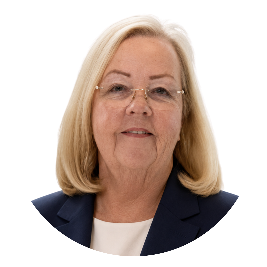 A portrait of an older woman with blonde hair and glasses wearing a navy blazer over a white top against a white background.