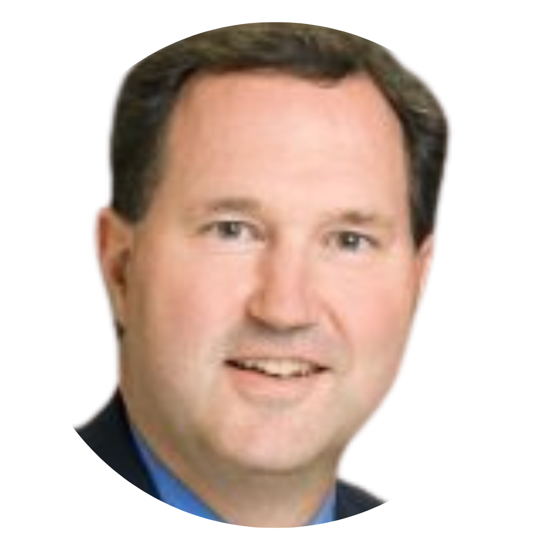 A close-up portrait of a man with short dark hair, smiling and wearing a navy suit with a light blue shirt, set against a white background.