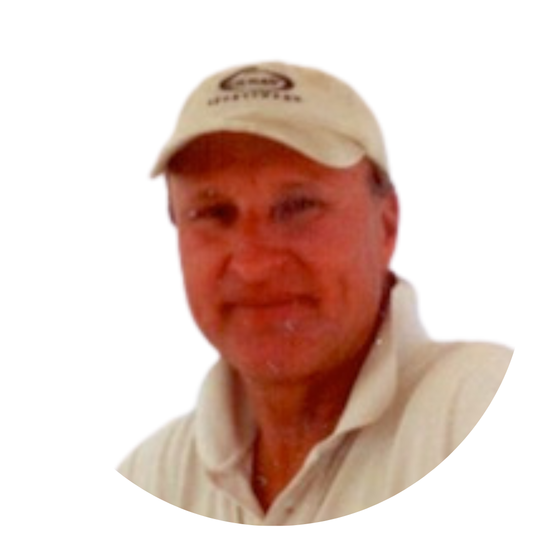 A man with short hair wearing a white polo shirt and a light-colored baseball cap, smiling at the camera. The image has a circular crop with a plain white background.