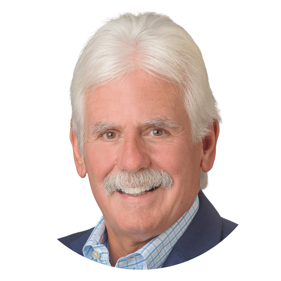 A headshot of a man with gray hair and a mustache, smiling at the camera. He is wearing a light blue checkered shirt under a dark blazer, set against a plain white background.