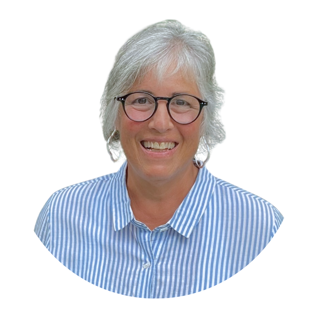 A woman with gray hair wearing glasses and a blue and white striped shirt, smiling against a white background. The image has a circular crop.