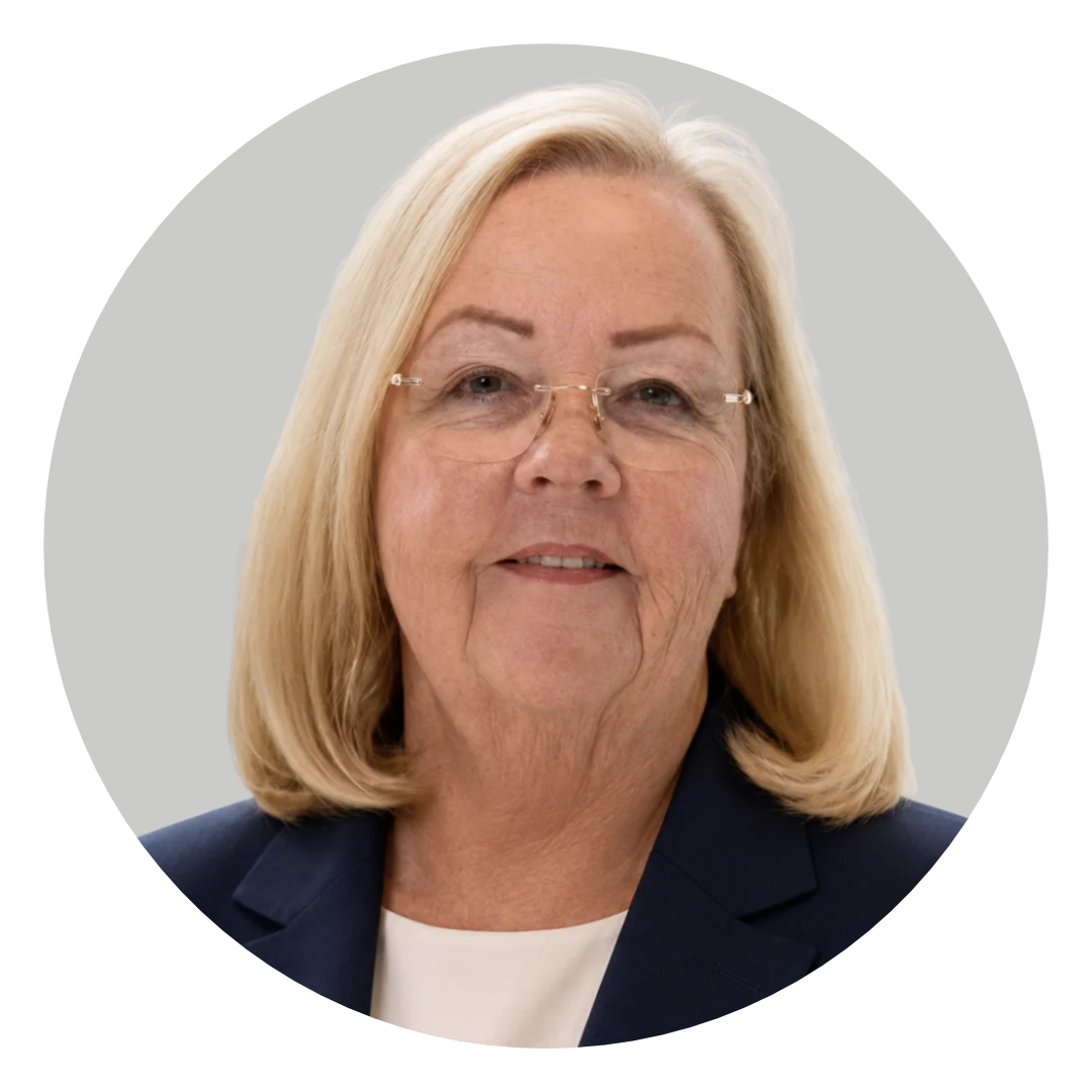 A head-and-shoulders portrait of an older woman with blonde hair and glasses, wearing a navy blazer against a light gray circular background.